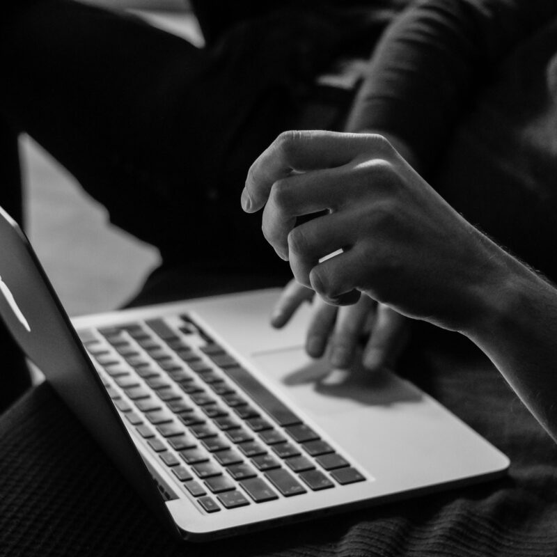 A black-and-white image of a user interacting with a laptop, highlighting content structuring and CMS workflow efficiency.