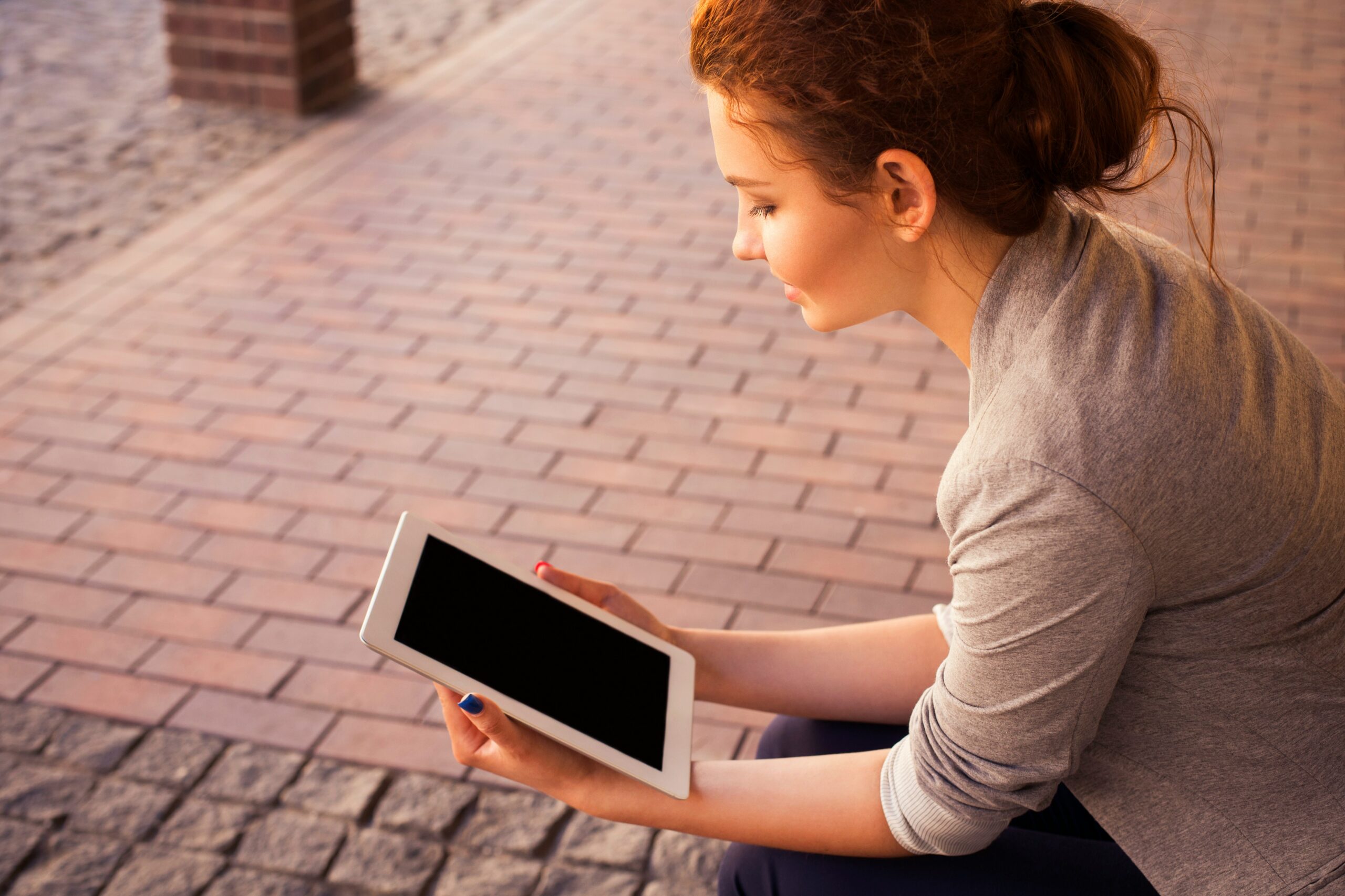 A woman using a tablet outdoors, emphasizing the user experience and mobile compatibility of different CMS options.