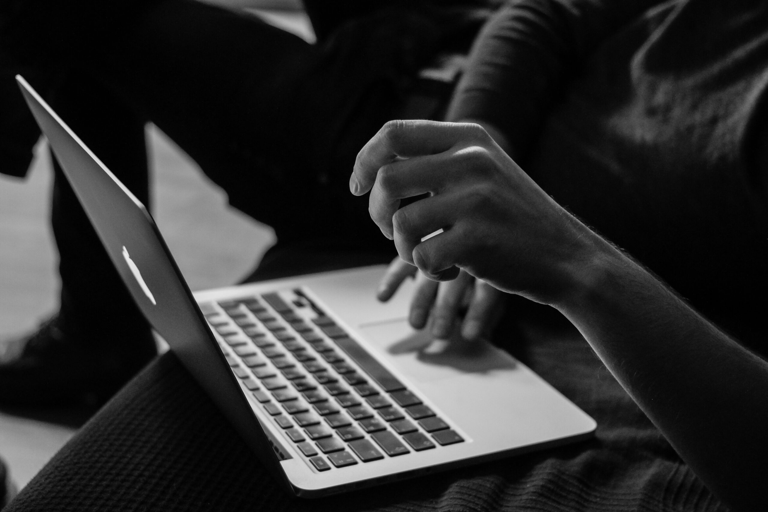 A black-and-white image of a user interacting with a laptop, highlighting content structuring and CMS workflow efficiency.