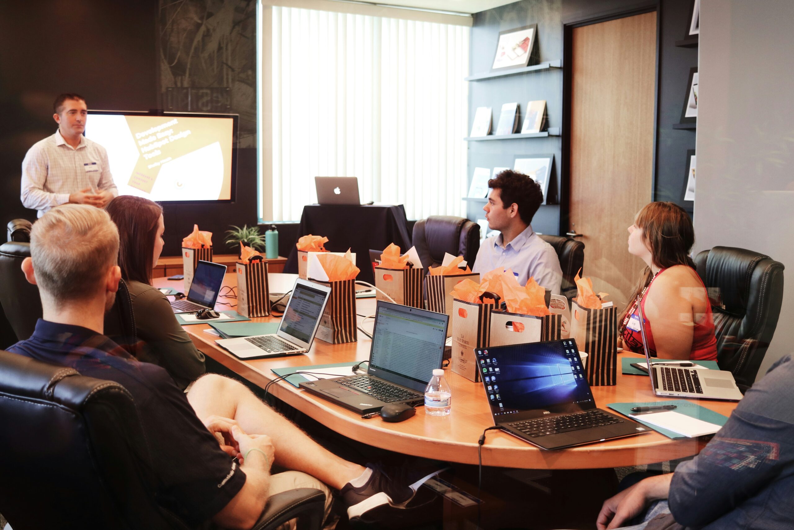 A business team in a meeting room with laptops, analysing CMS options to determine the best fit for their website needs.