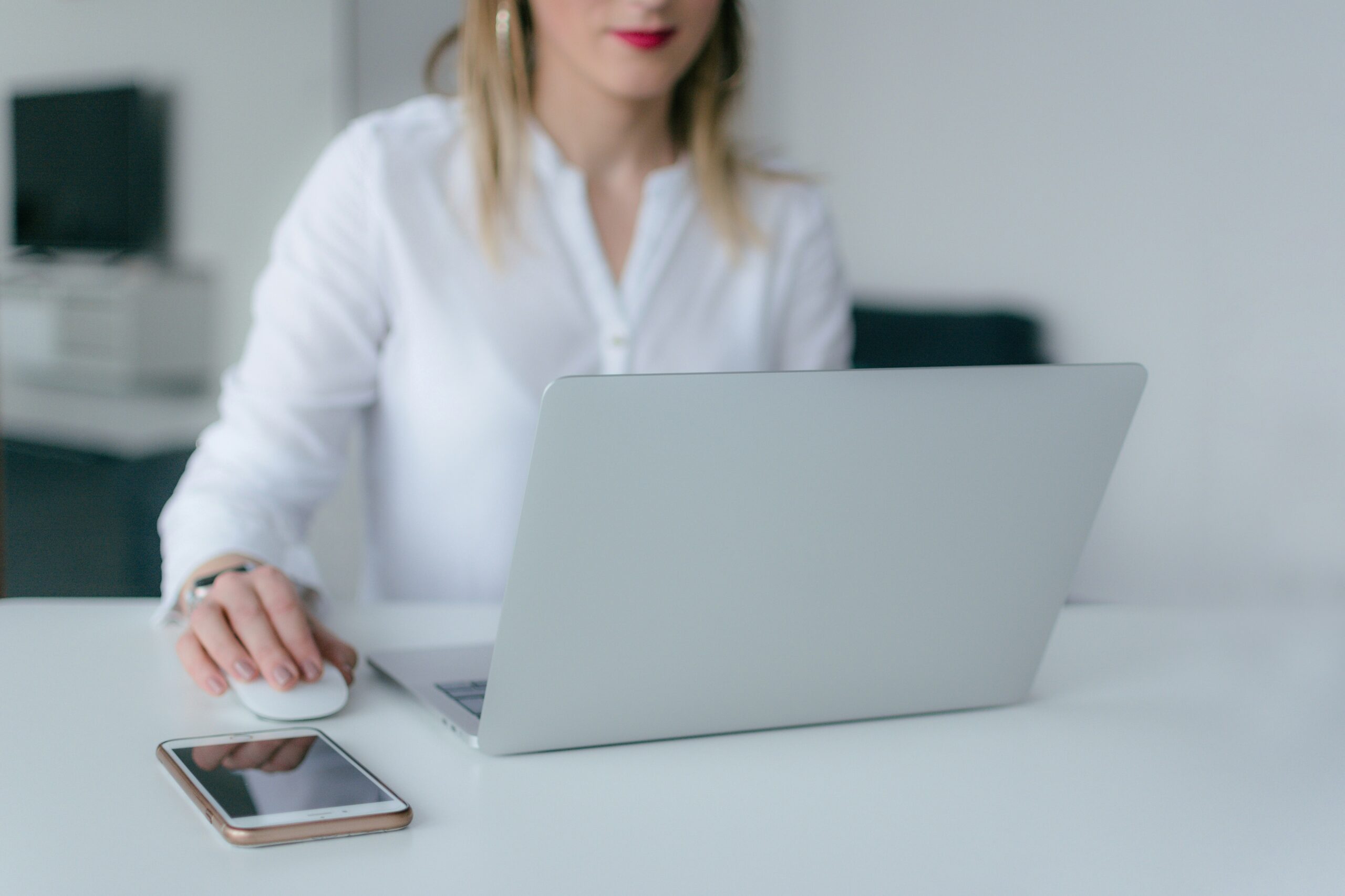 A woman using a laptop with a smartphone nearby, representing the user-friendly interface of CMS platforms for small businesses.