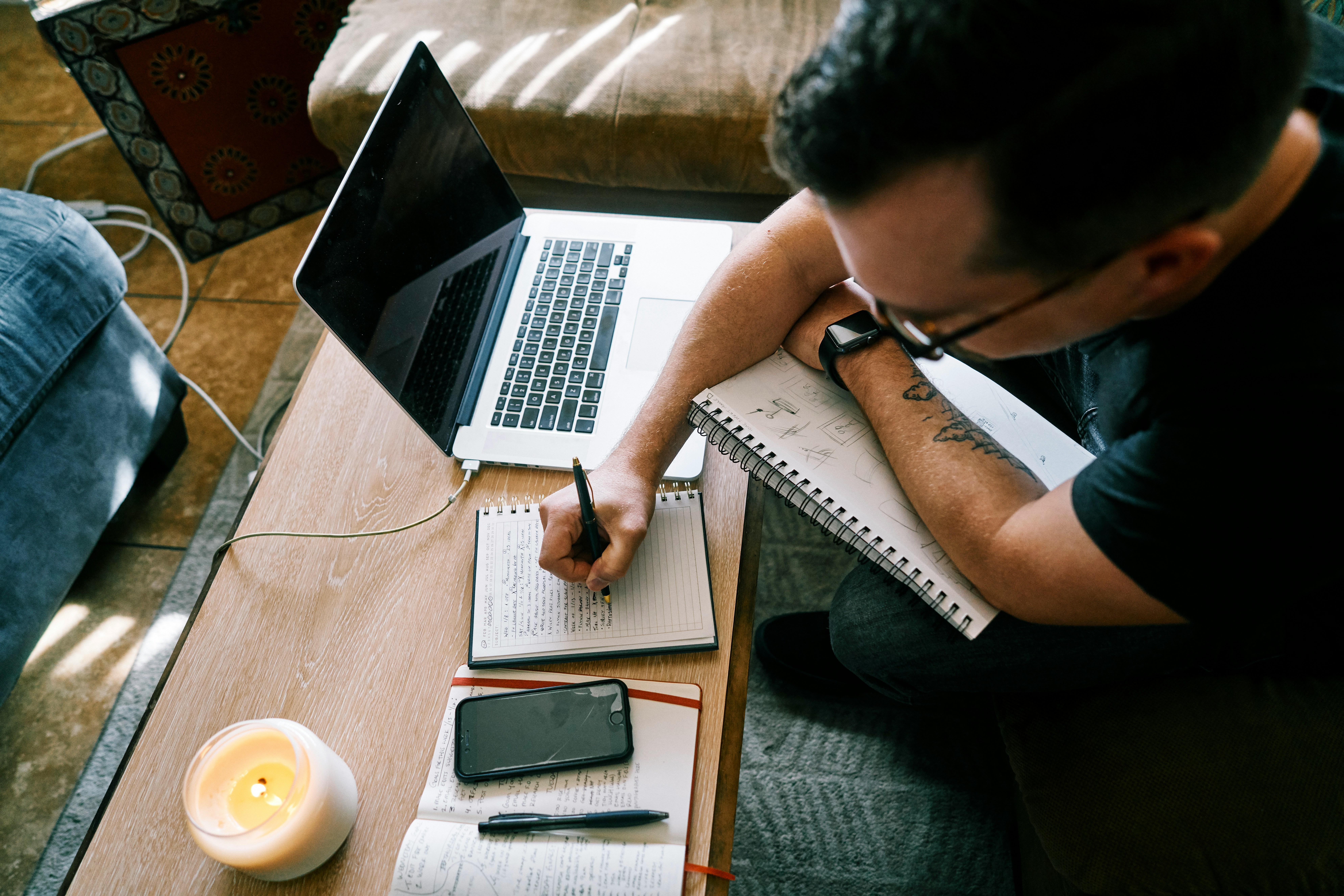 A person working on a laptop with a notebook and a phone, highlighting the importance of using SEO strategies to optimize content for e-commerce success.