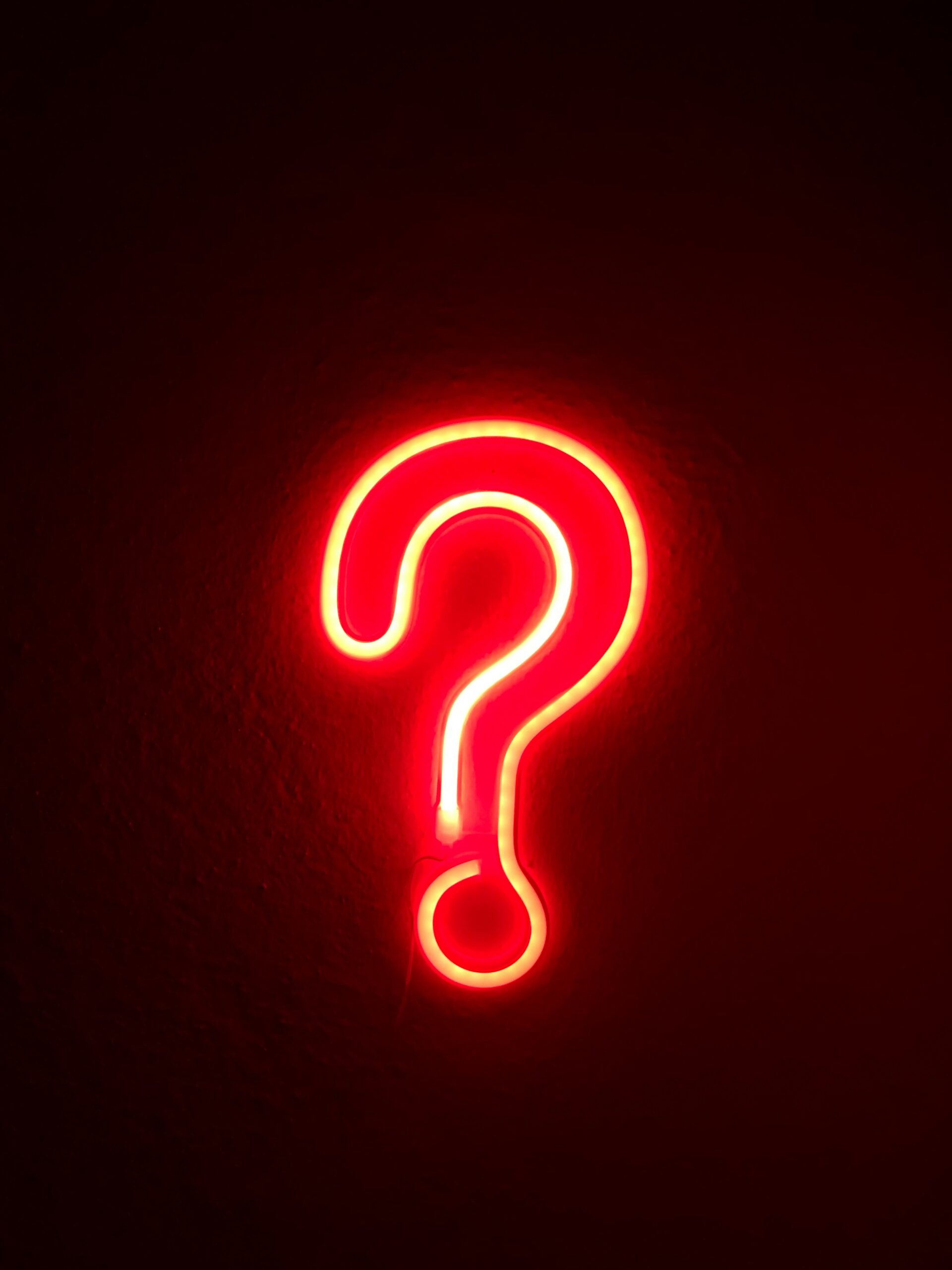 A glowing red question mark, highlighting frequently asked questions about custom CMS development services and their benefits.