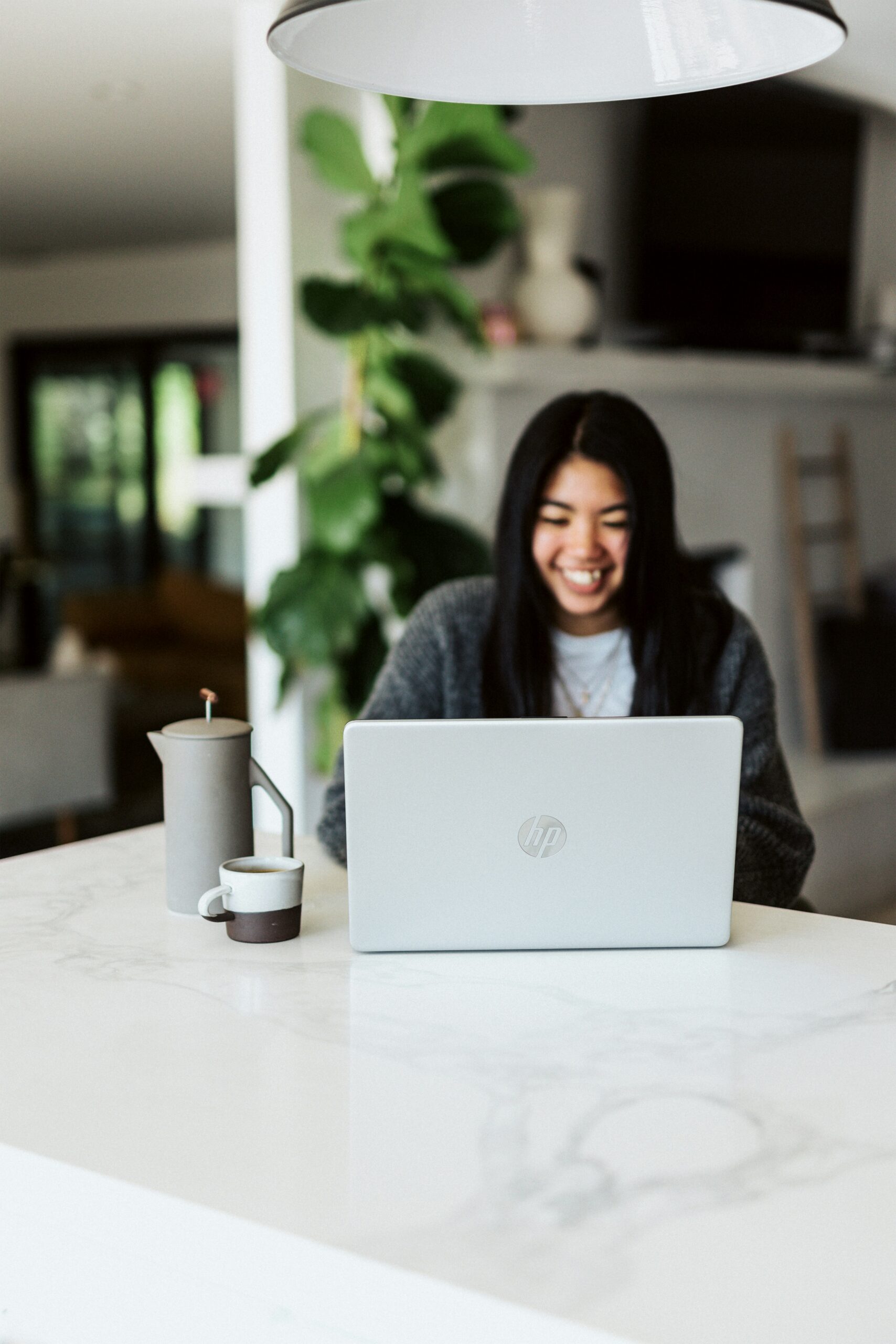 A person smiling while working on a laptop in a well-lit space, representing the connection between digital engagement and SEO optimization for e-commerce success.