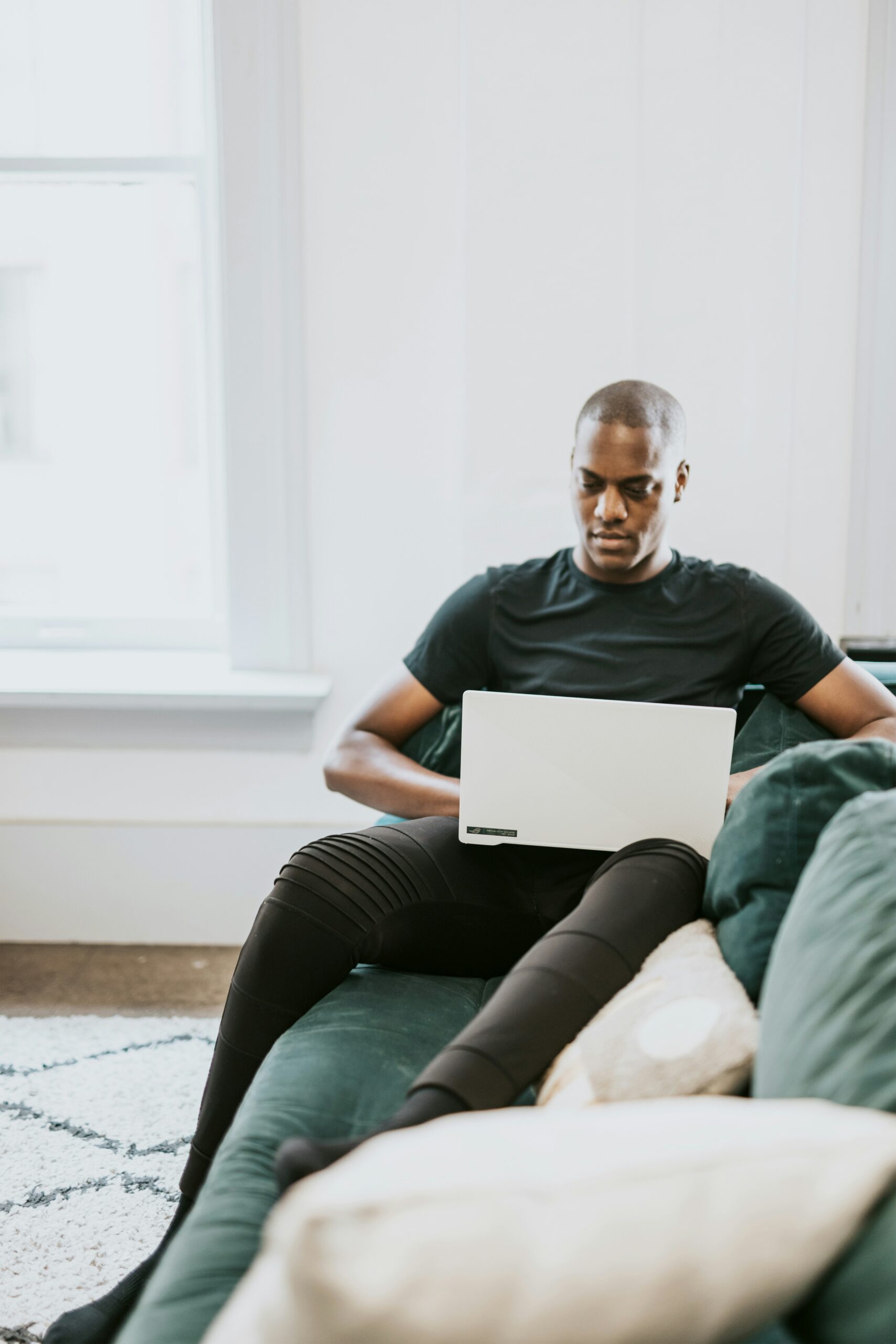 A man working on a laptop while sitting on a couch, illustrating the flexibility of web design services in creating user-friendly and adaptive CMS solutions.