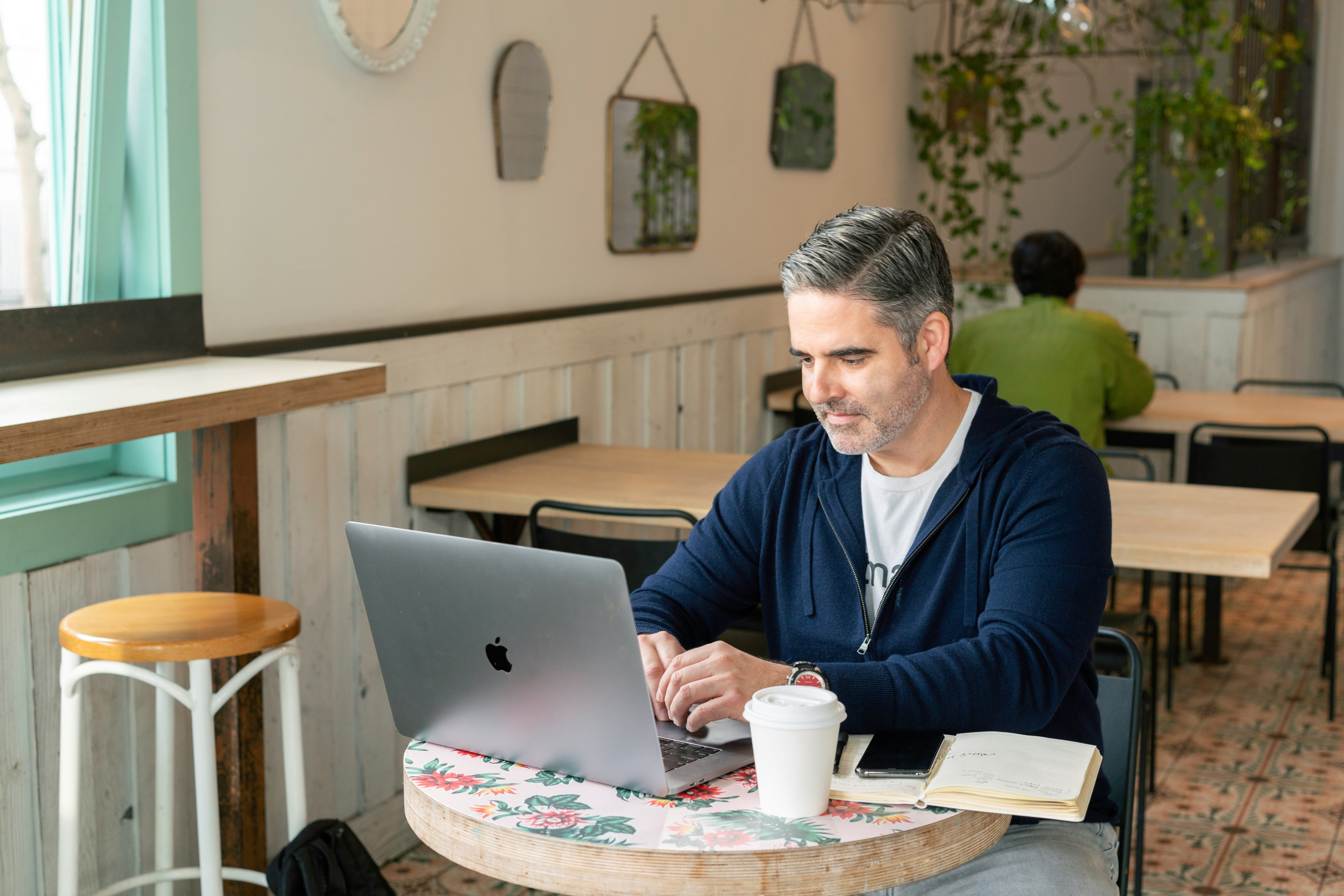 A person working at a café with a laptop, illustrating the convenience of managing a local or national web design CMS from anywhere for business owners.