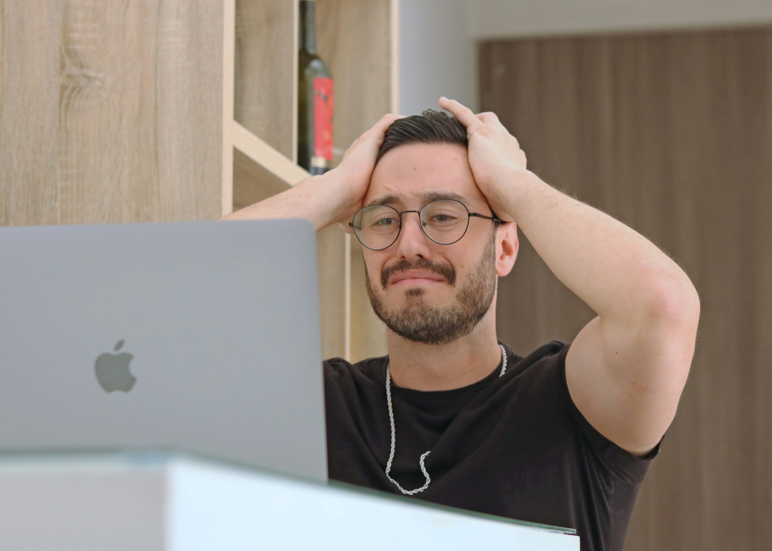 A person frustrated while working on a laptop, representing common mistakes in SEO web design, such as poor site structure, slow load times, or lack of mobile optimization.