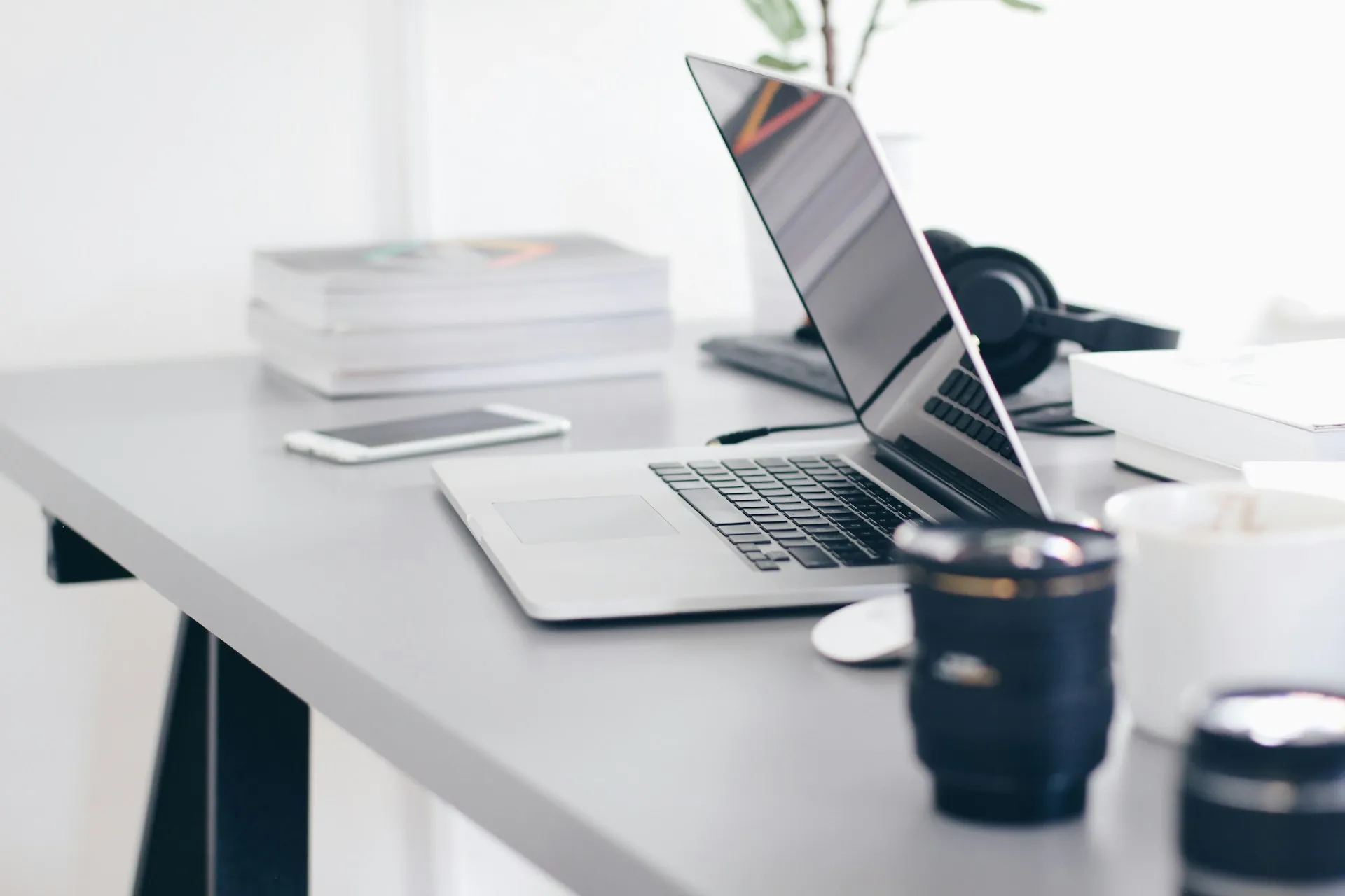 A modern workspace with a sleek laptop, smartphone, books, and camera lenses, symbolizing the process of evaluating skills and expertise in a professional setting.