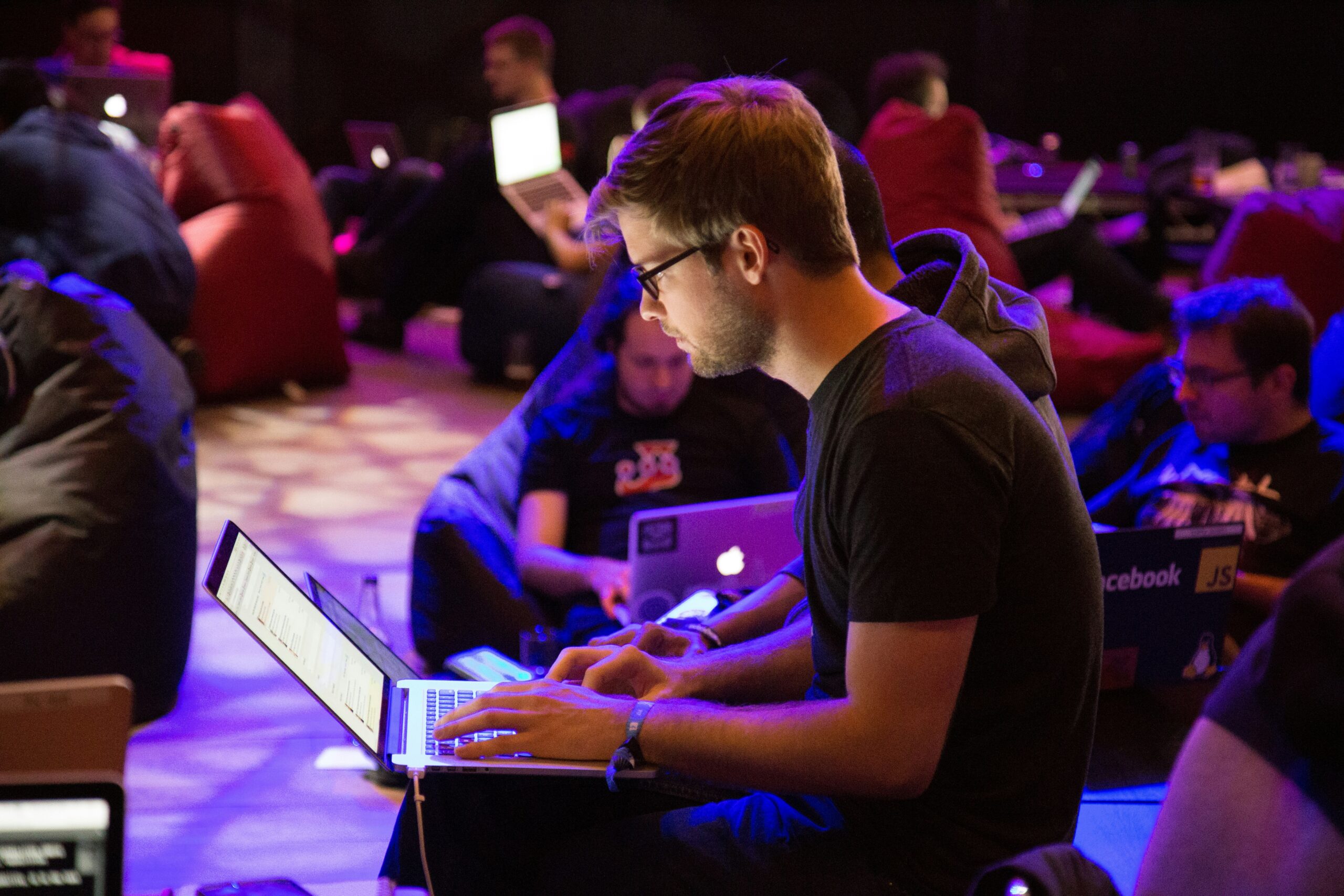 Developers collaborating in a dimly lit workspace, focusing on user experience and front-end solutions on their laptops.