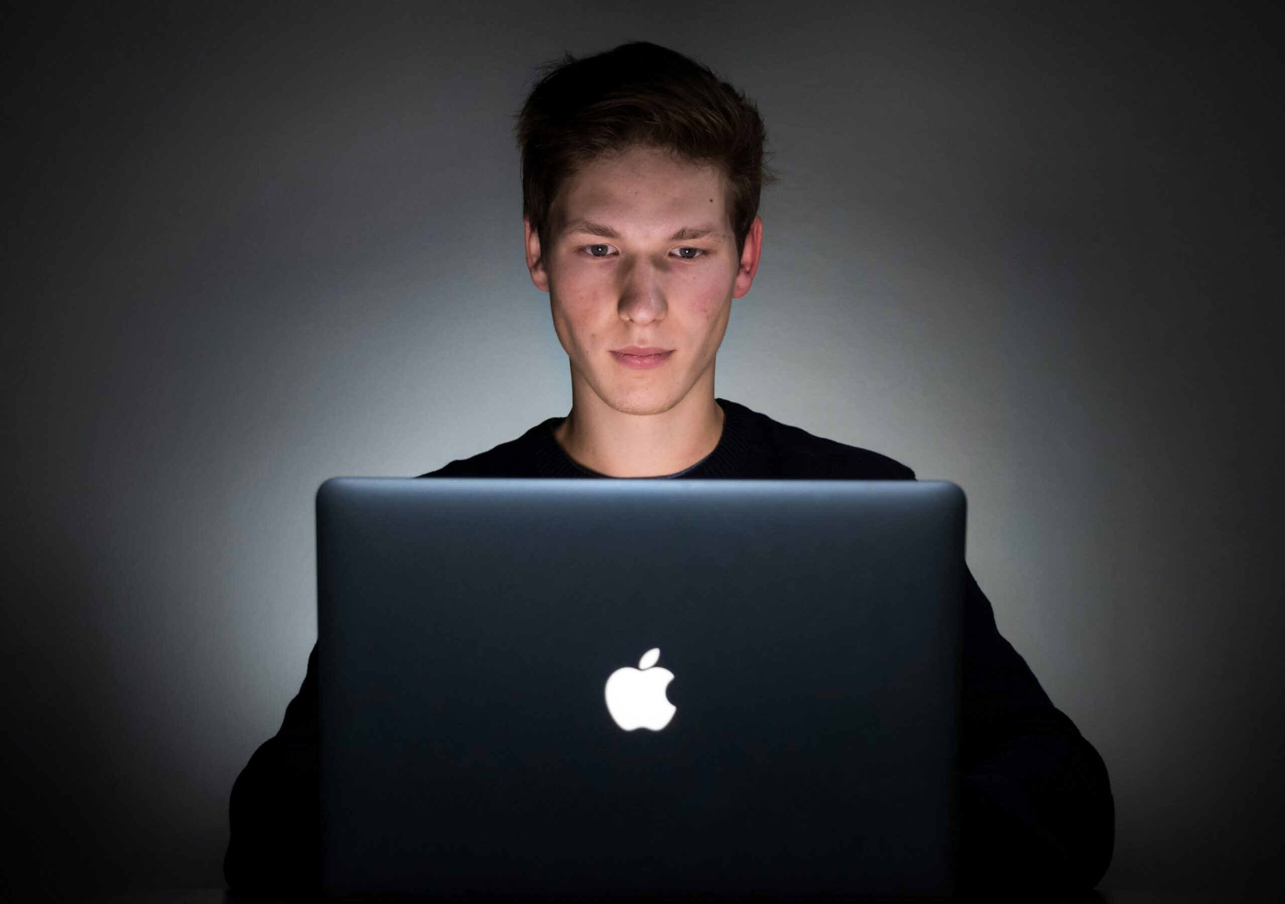 A focused young man working on a laptop in a dimly lit environment, emphasizing the importance of front-end performance optimization in creating efficient and fast-loading websites.