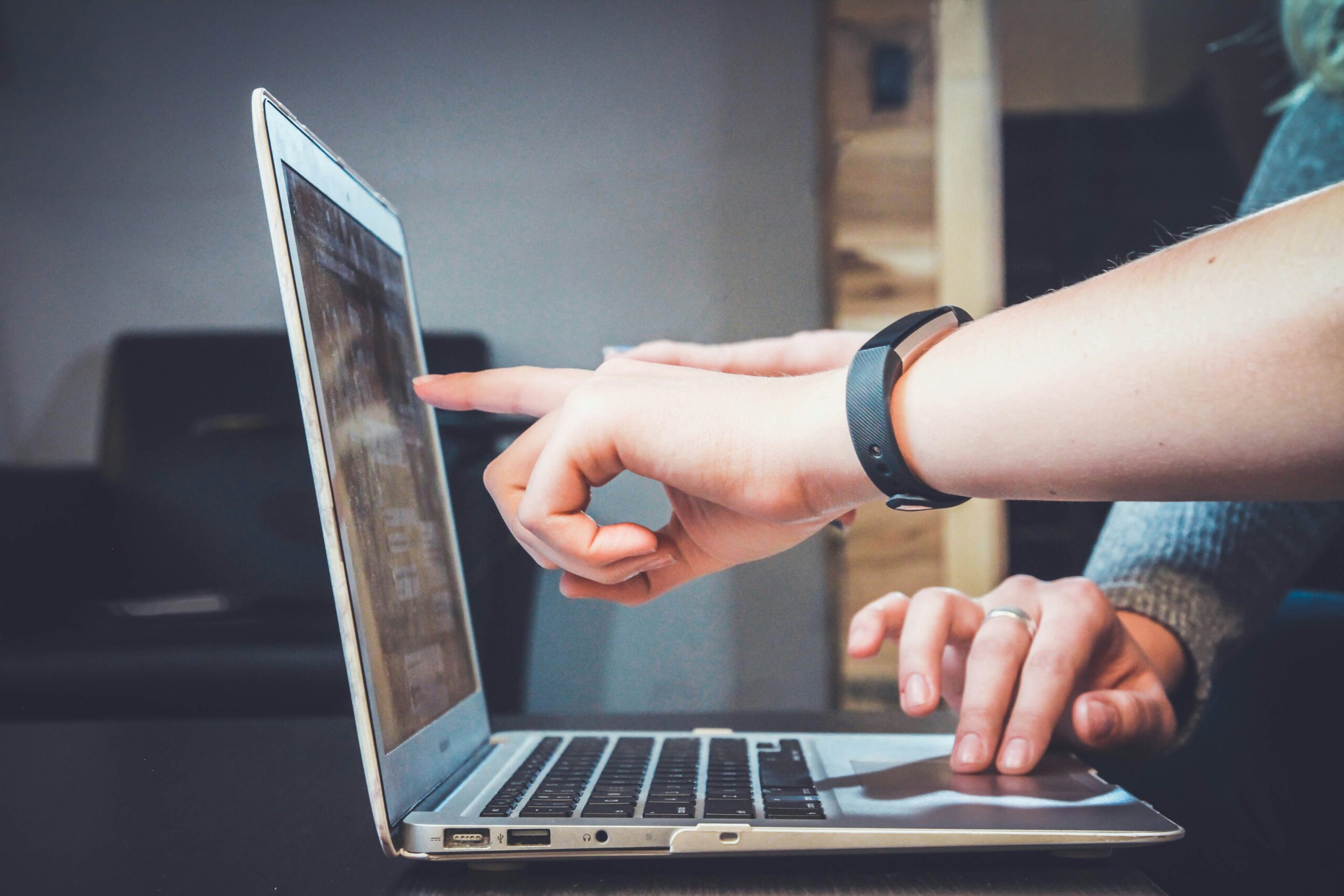 Two people collaborating on a laptop, with one pointing at the screen and the other typing, discussing design elements for accessibility and visual appeal.