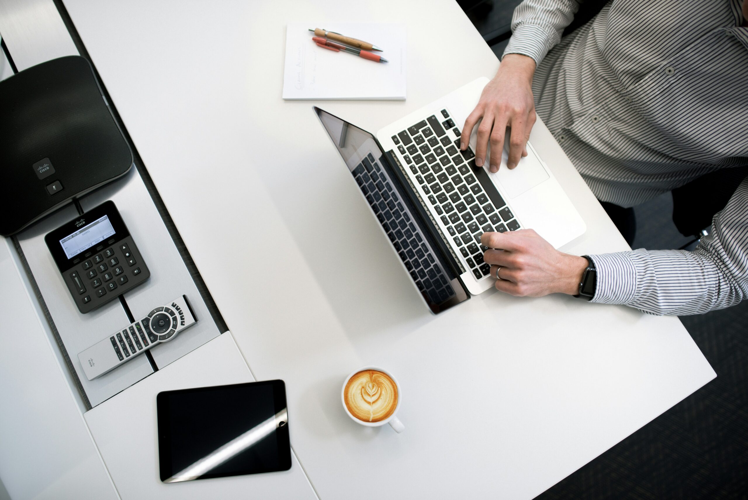 Professional working on a laptop at a modern office desk, representing cost implications and resource availability in project management.