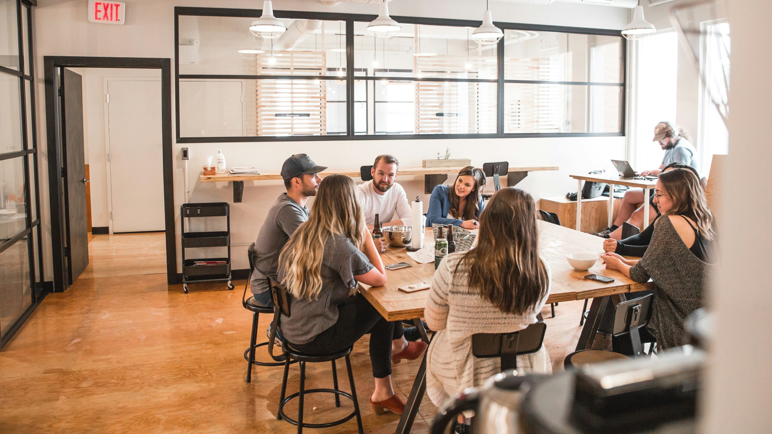 A group of people gathered around a wooden table in a modern office space, discussing ideas and collaborating, representing performance considerations in front-end technologies.