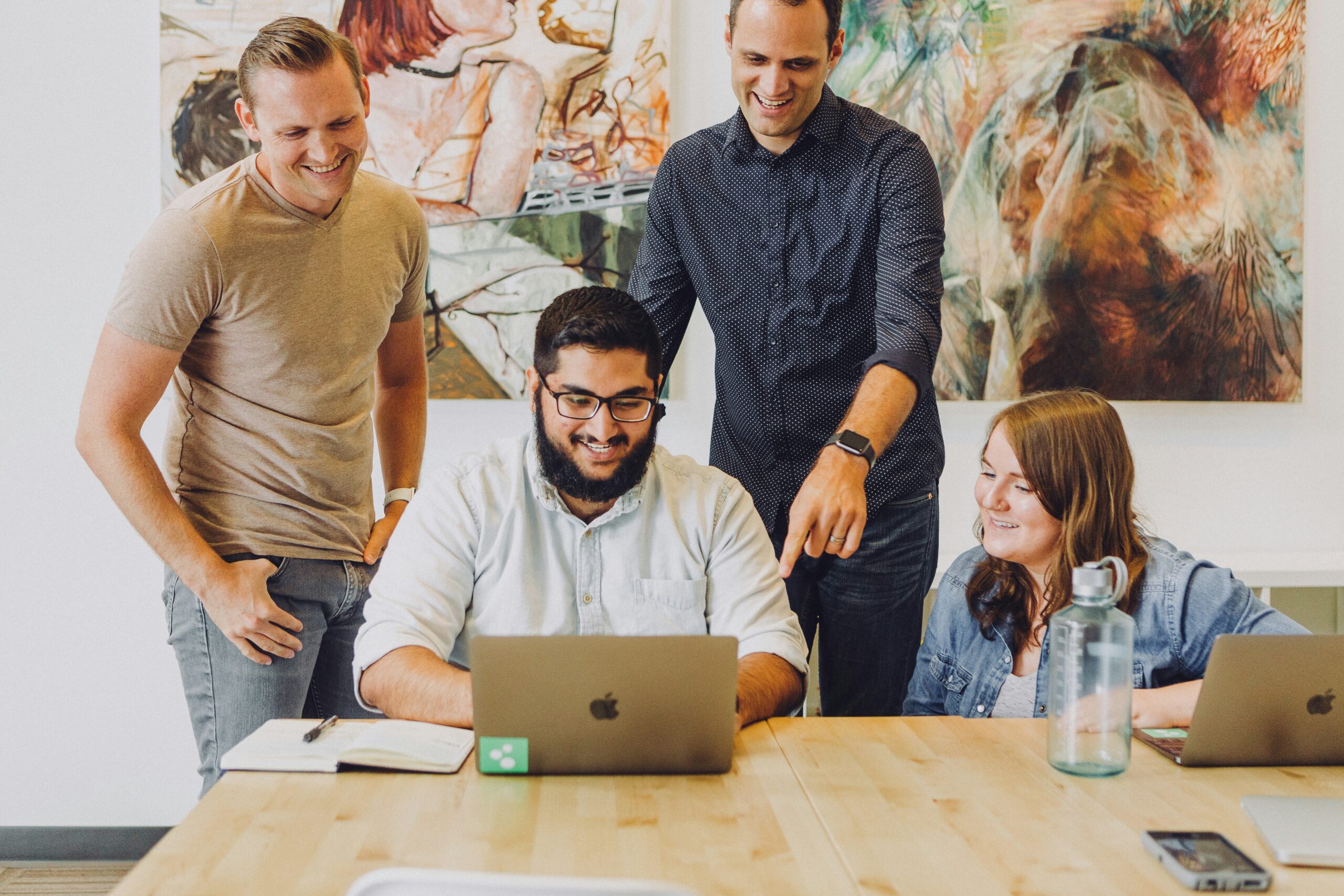 A collaborative team discussion around a laptop, debunking common myths and misconceptions about front-end frameworks.