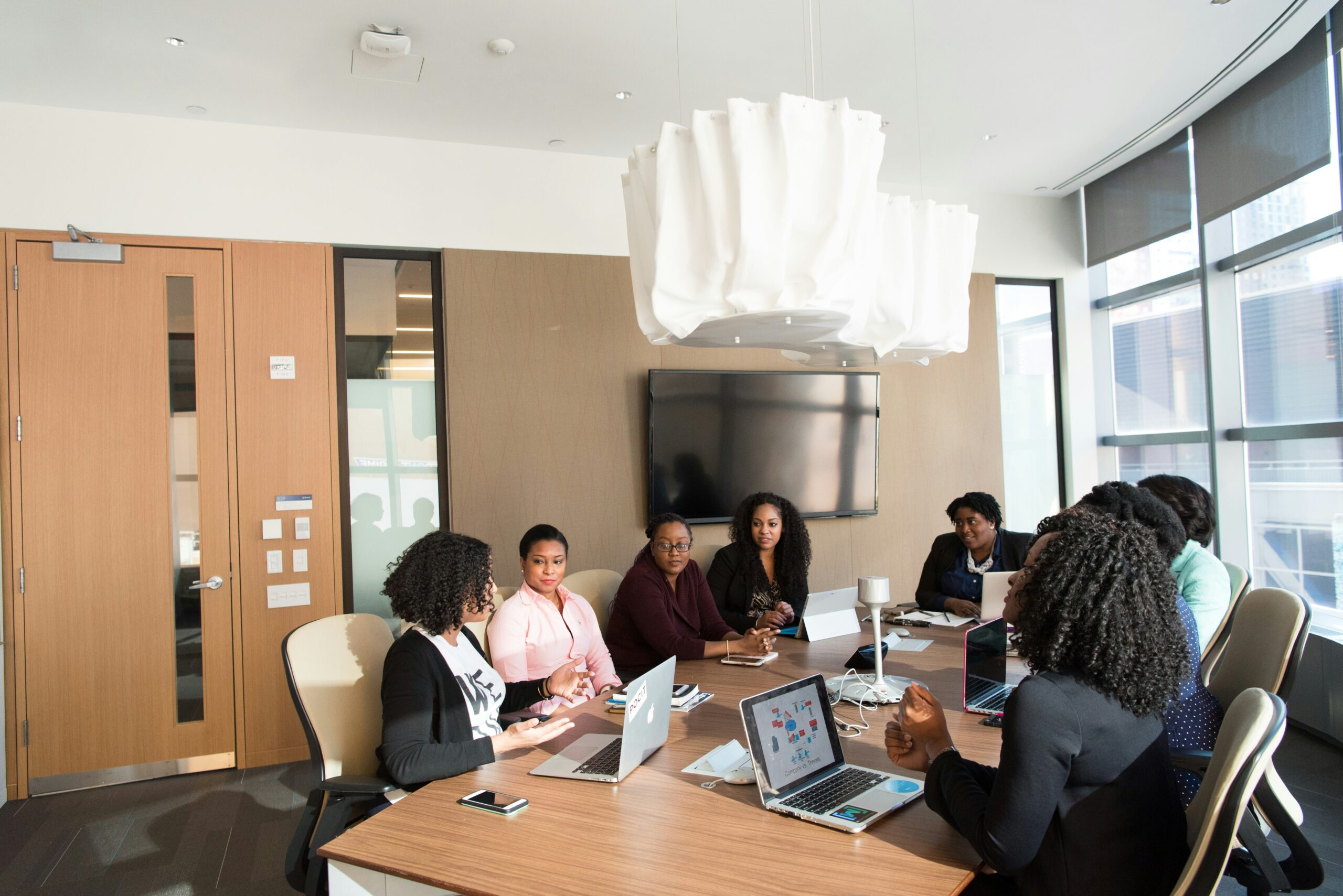 A diverse group of professionals in a modern conference room discussing project requirements, with laptops and notes on the table to streamline planning and execution.