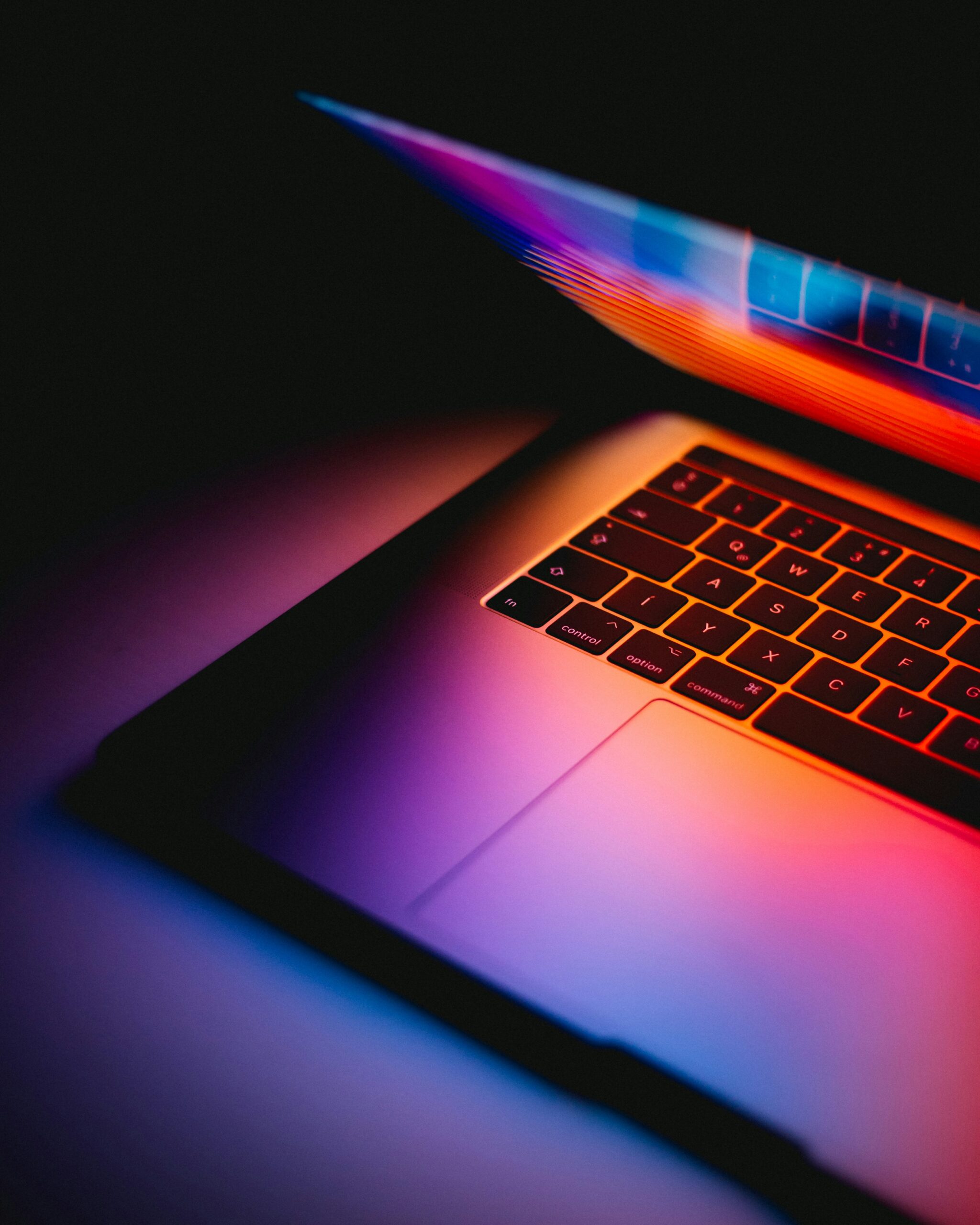 A partially closed laptop glowing with vibrant colors in a dark setting, symbolizing the critical need to address security vulnerabilities and protect sensitive data. | Day by Day Digital A partially closed laptop glowing with vibrant colors in a dark setting, symbolizing the critical need to address security vulnerabilities and protect sensitive data.