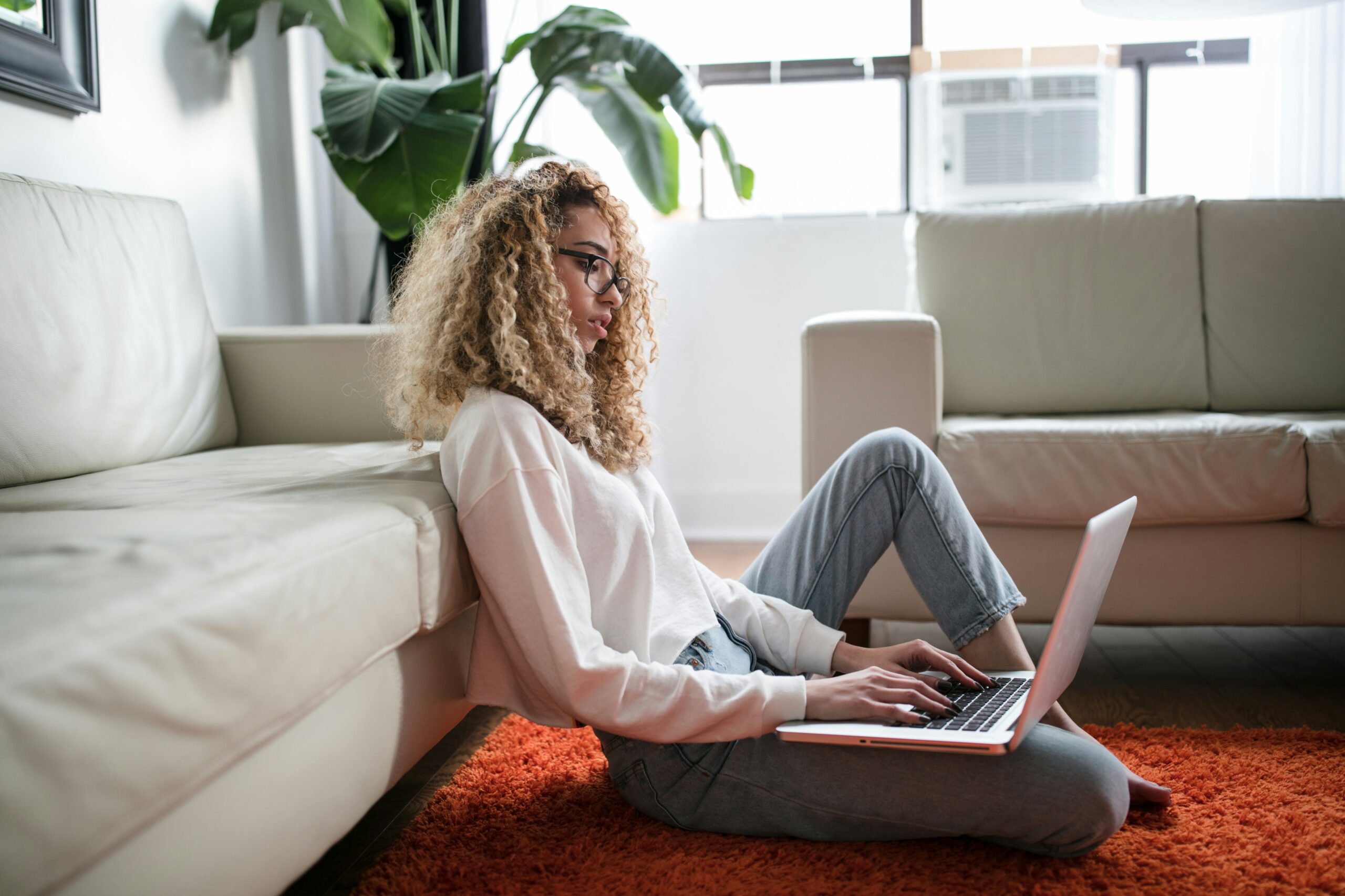 A woman sits comfortably on an orange rug using a laptop, focusing on optimizing website navigation to support better user experience and SEO outcomes. | Day by Day Digital A woman sits comfortably on an orange rug using a laptop, focusing on optimizing website navigation to support better user experience and SEO outcomes.