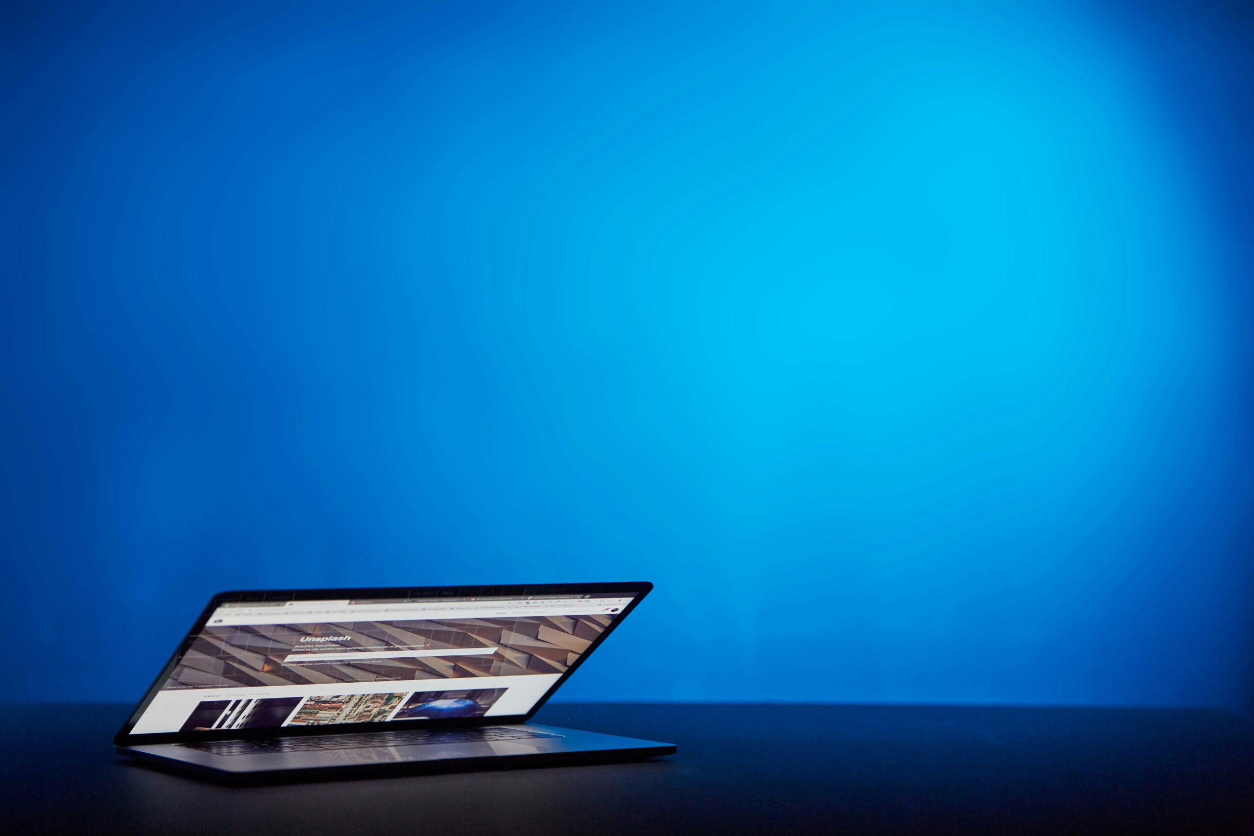 A sleek laptop partially open against a bold blue backdrop, symbolizing the contrast between custom-optimized website performance and the limitations of pre-built templates. | Day by Day Digital A sleek laptop partially open against a bold blue backdrop, symbolizing the contrast between custom-optimized website performance and the limitations of pre-built templates.