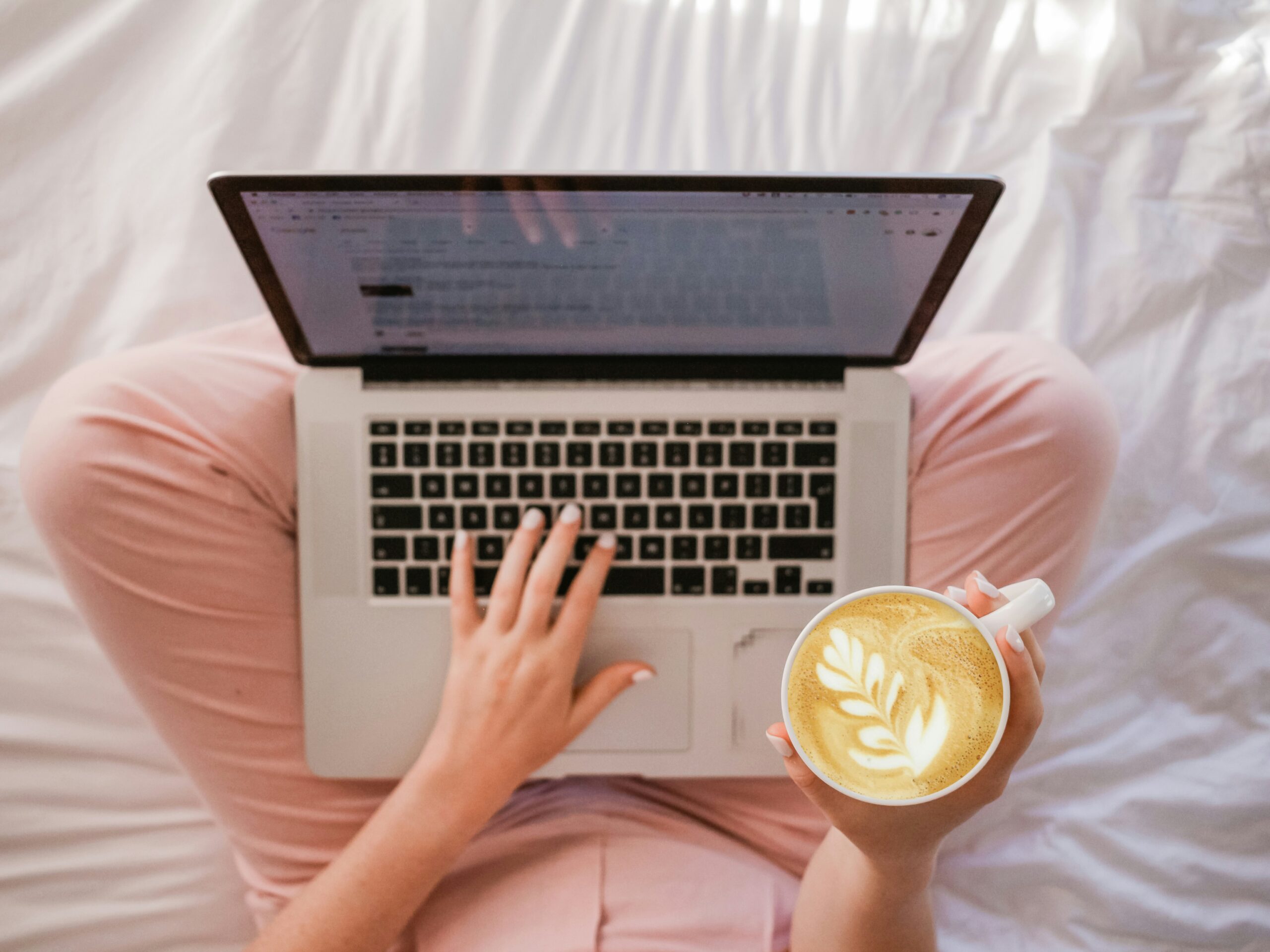 A person working on a laptop with a coffee in hand, representing how strategic header tag implementation enhances user experience and content readability.