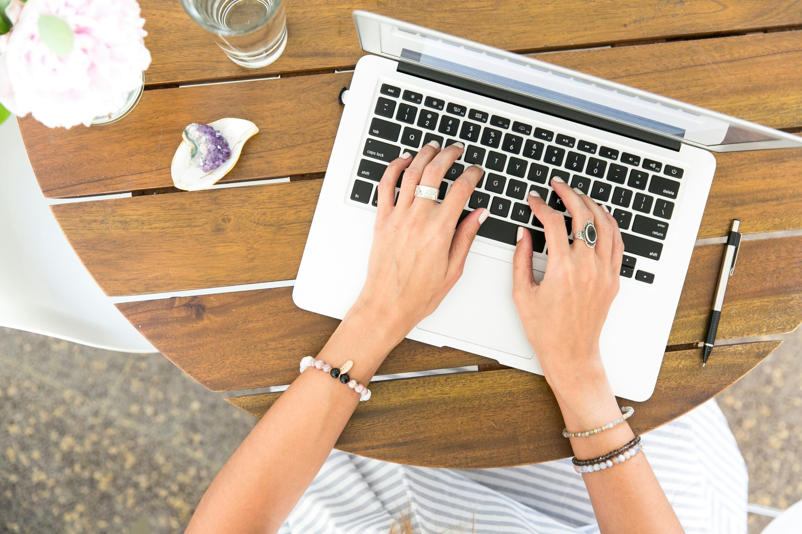 A person types on a laptop at a stylish outdoor table, illustrating how consistent content creation can boost brand awareness within the local community. | Day by Day Digital A person types on a laptop at a stylish outdoor table, illustrating how consistent content creation can boost brand awareness within the local community.