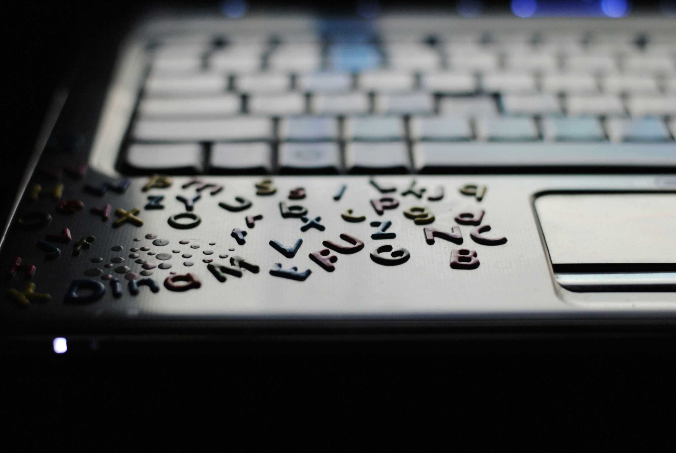 Close-up of colorful alphabet stickers on a laptop, symbolizing the importance of thoughtful typography in maintaining brand identity and ensuring legibility. | Day by Day Digital Close-up of colorful alphabet stickers on a laptop, symbolizing the importance of thoughtful typography in maintaining brand identity and ensuring legibility.