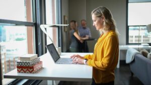 A woman typing on a laptop in a bright office space illustrates the focus and planning involved in following best practices for creating effective SEO content.