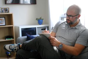 A man thoughtfully writing in a notebook on a couch represents the careful selection process involved in finding the right SEO content writer for your business.