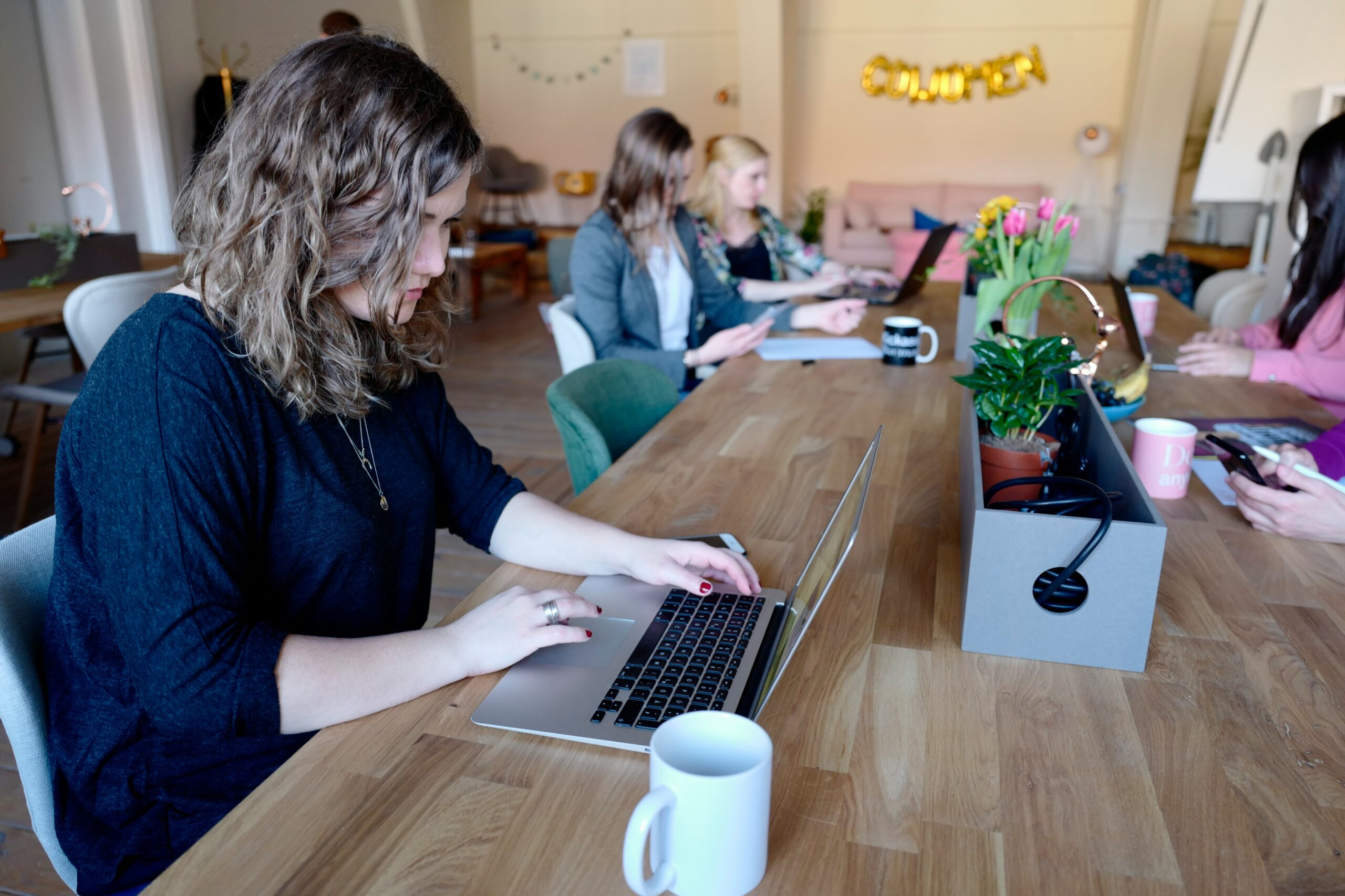 Team of professionals working on laptops in a collaborative workspace, representing the importance of SEO content marketing services for business growth. | Day by Day Digital Team of professionals working on laptops in a collaborative workspace, representing the importance of SEO content marketing services for business growth.