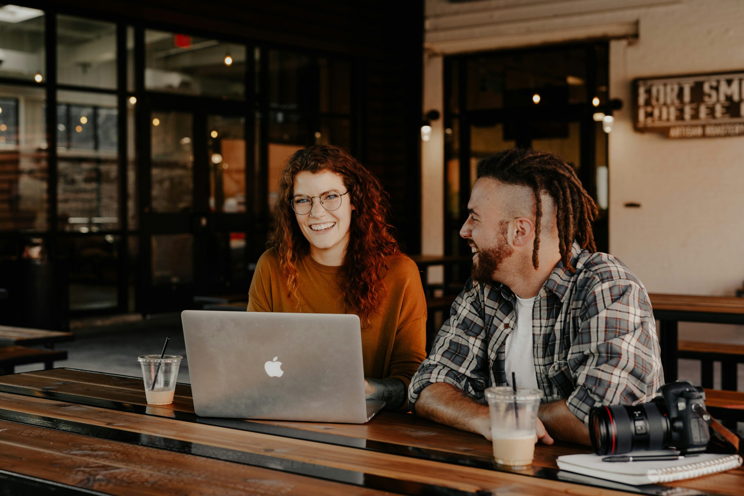 Two professionals discussing SEO strategies on a laptop at a café, symbolizing collaboration in choosing the right SEO provider for e-commerce success.