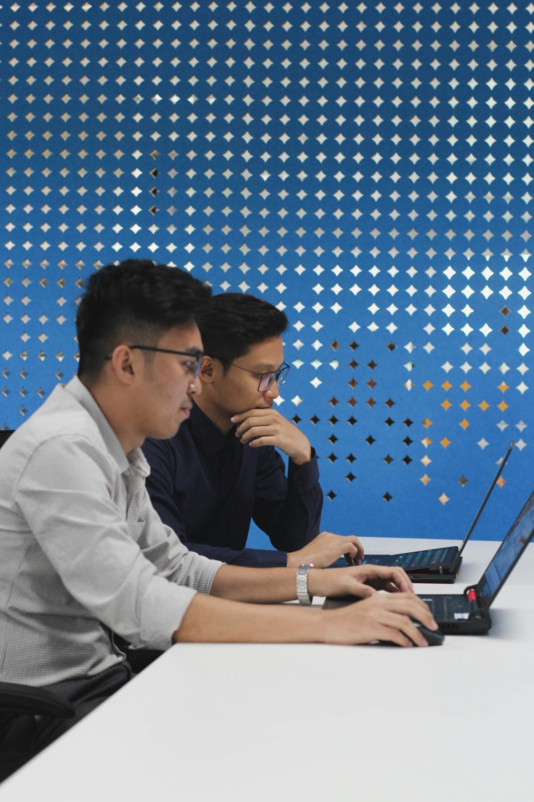 Two professionals focused on their laptops, collaborating on diverse link building strategies to boost SEO effectiveness.