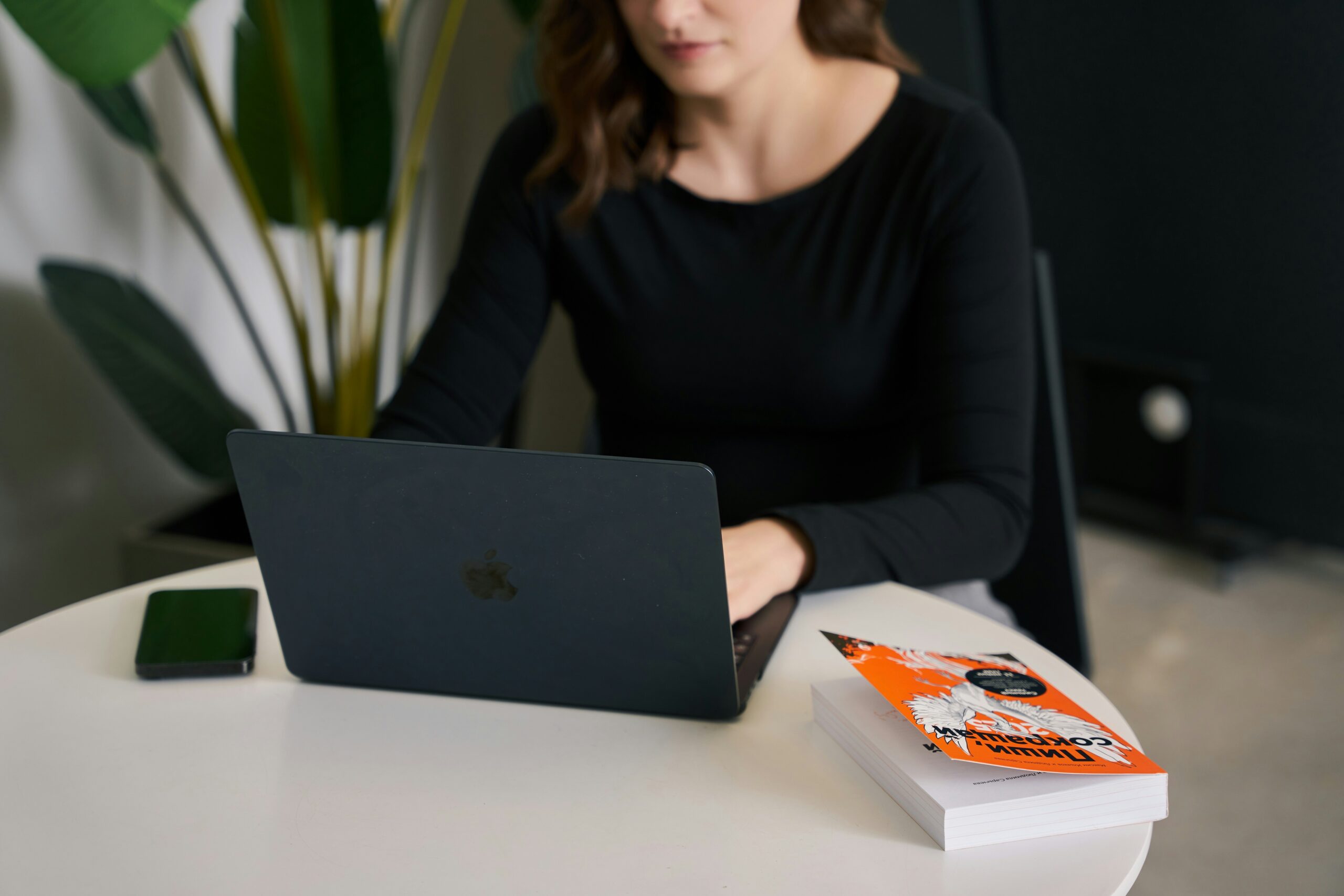 A woman working on a laptop beside a marketing book, symbolizing how local SEO content agencies provide personalized strategies tailored to boost neighborhood-level business visibility. | Day by Day Digital A woman working on a laptop beside a marketing book, symbolizing how local SEO content agencies provide personalized strategies tailored to boost neighborhood-level business visibility.